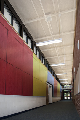 The mixture of primary red, blue, and yellow colored panels in the hallway of Ogden Elementary School break up the space and create a stimulating effect for children.
